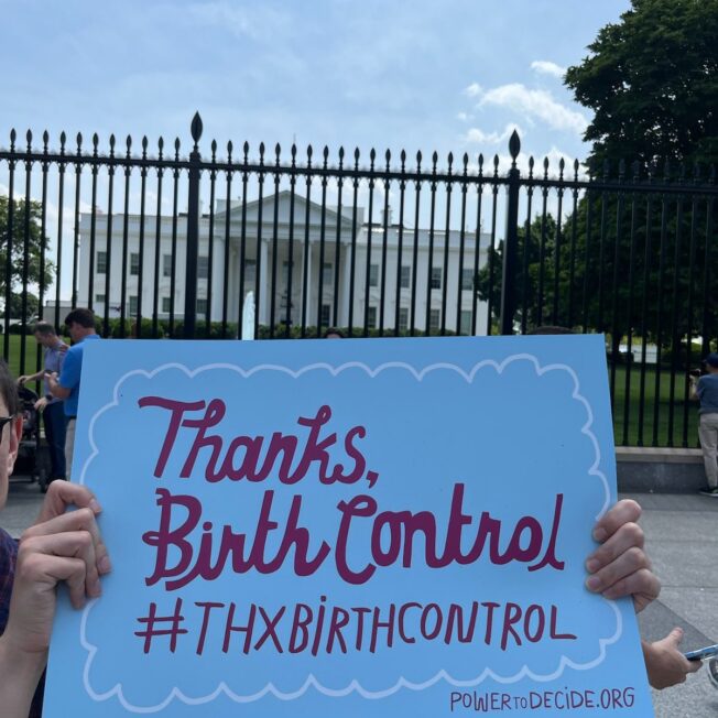 A sign says "Thanks, Birth Control" held in front of the White House.