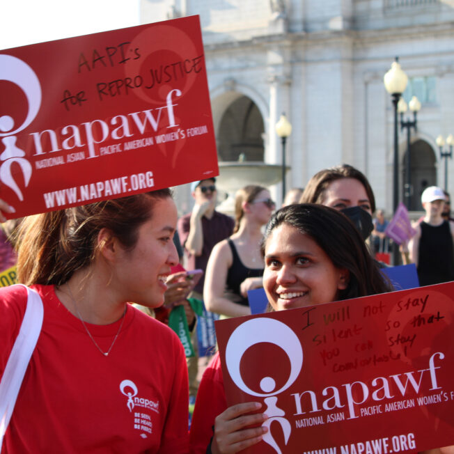 Two Asian American women have a conversation during a rally.