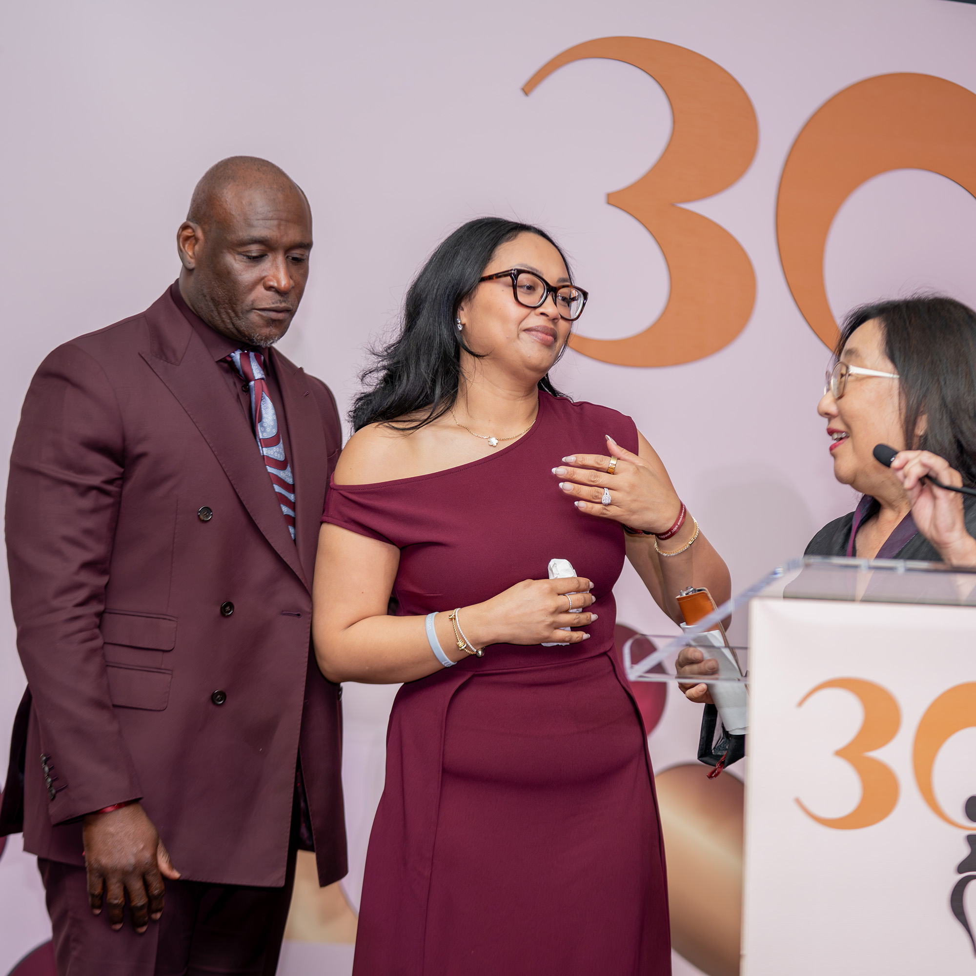 A photograph of Christine Wells-Wonsley, a Black and Filipina woman, being greeted on stage at NAPAWF's 30th anniversary event with her husband.